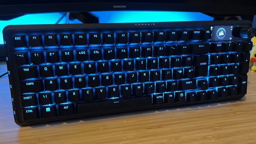 Corsair Vanguard Pro 96 gaming keyboard on a wooden desk with blue backlighting