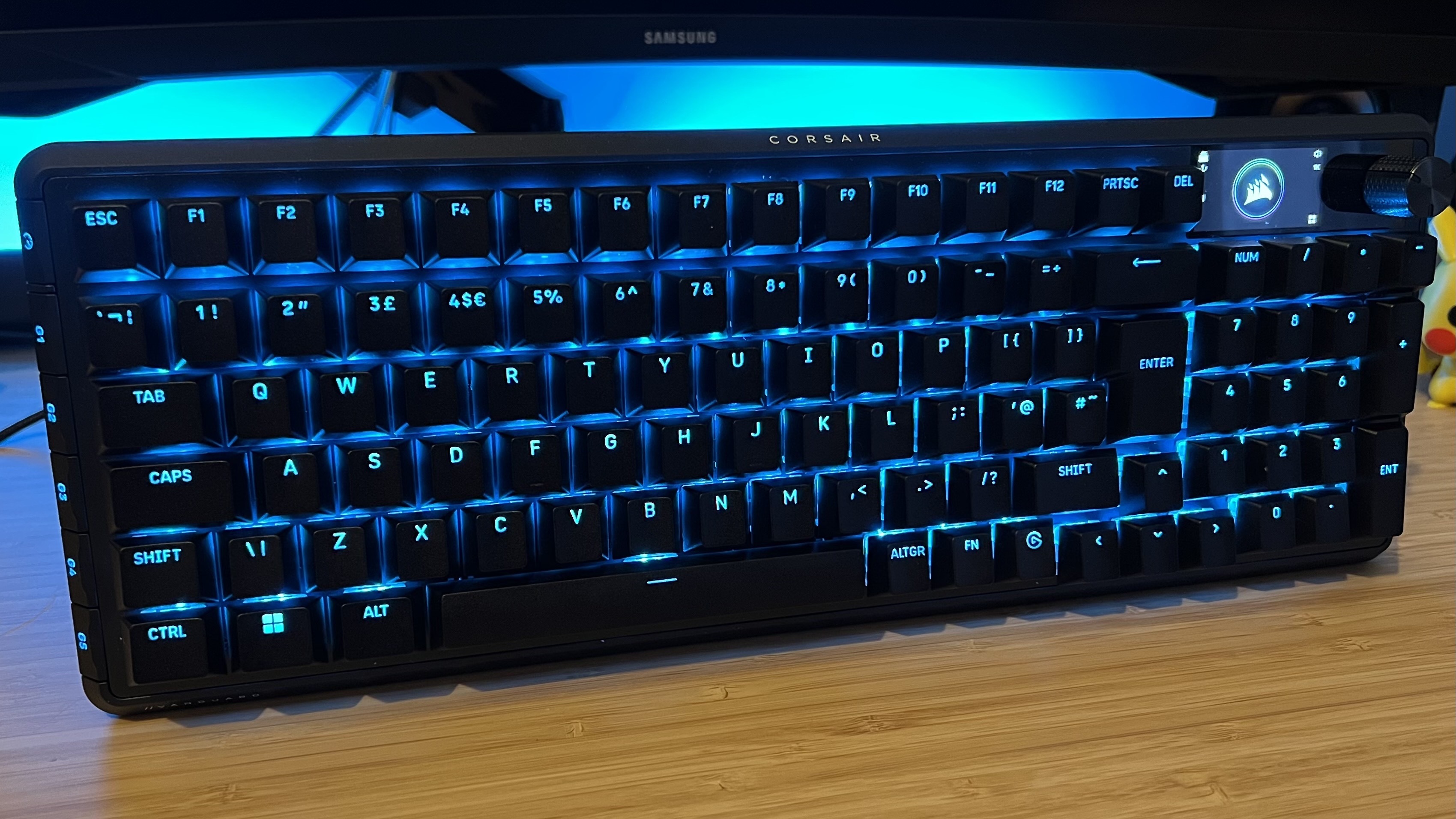 Corsair Vanguard Pro 96 gaming keyboard on a wooden desk with blue backlighting
