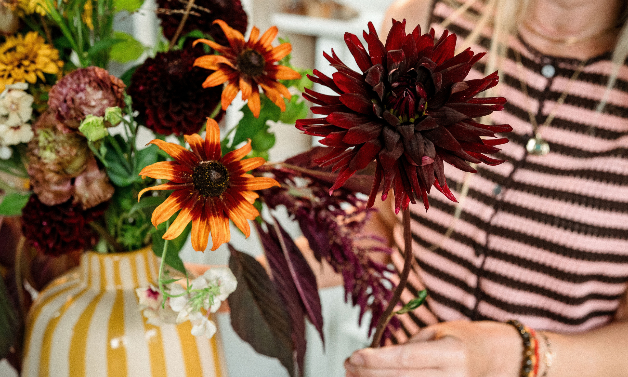 Autumn flowers, dahlias and rudbeckia in yellow stripe vase