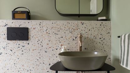 green bathroom with terrazzo tiles and green basin, mirrored cabinet and globe wall lights with a Roberts radio