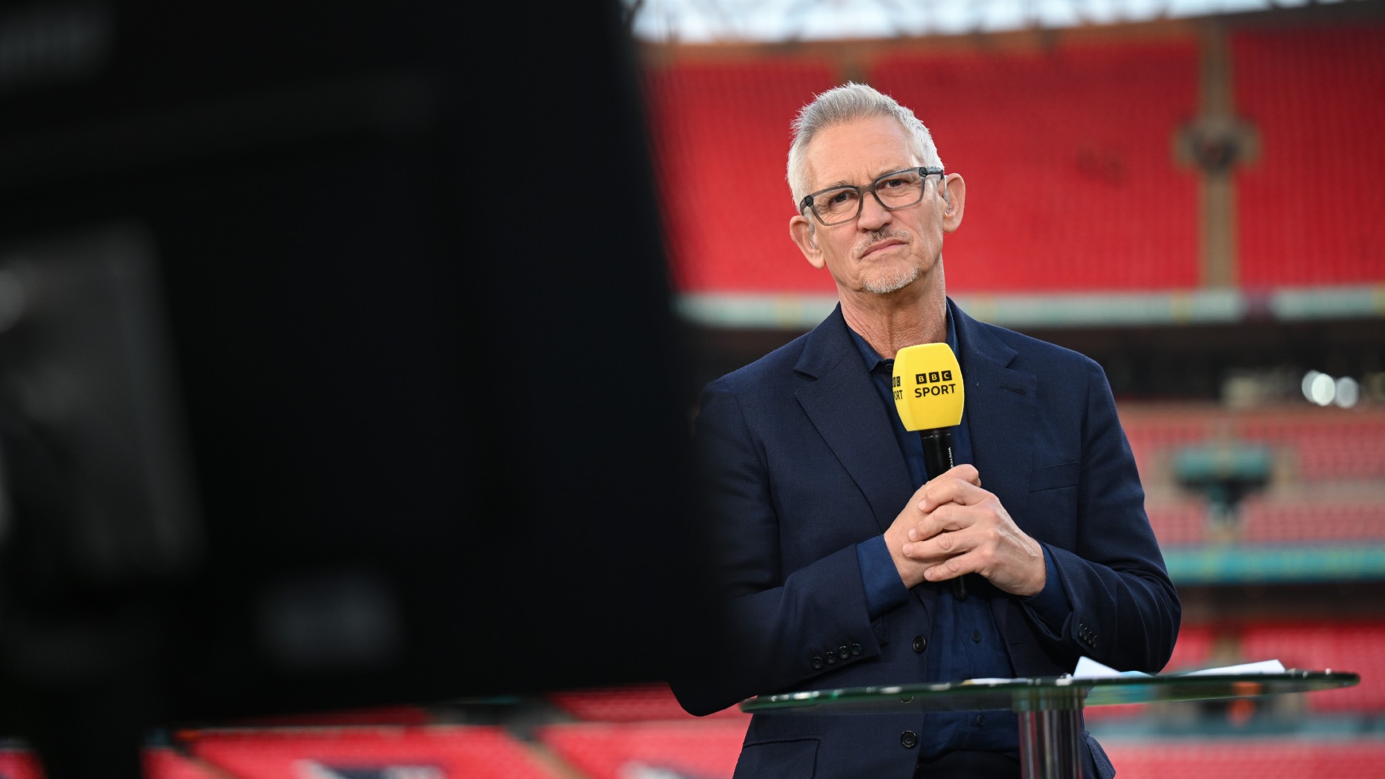 Gary Lineker looks towards a screen while presenting from Wembley Stadium 