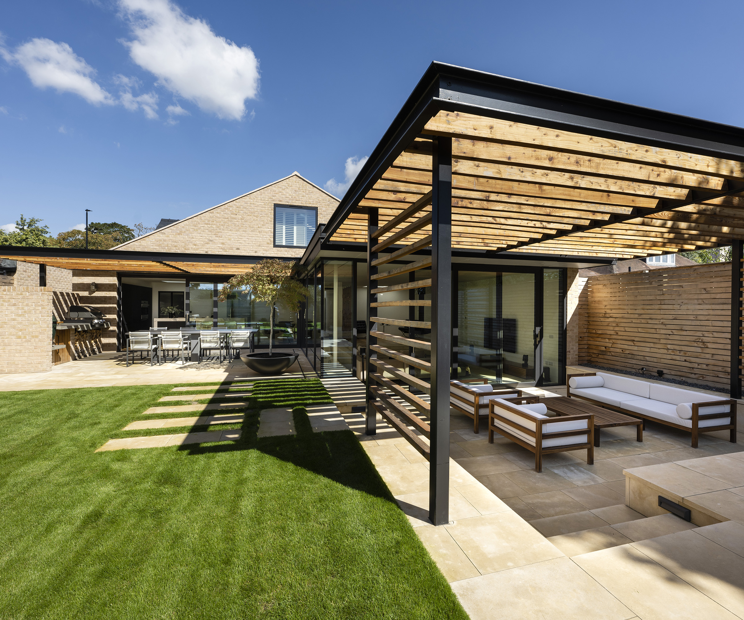 A covered sunken patio area next to a pristine lawn