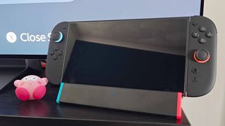 SIWIQU Nintendo Switch 2 dock with handheld on top next to shocked Kirby figure on black TV bench.