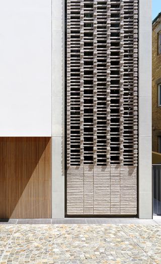 An exterior view of a white residential building with stacked wooden crate design
