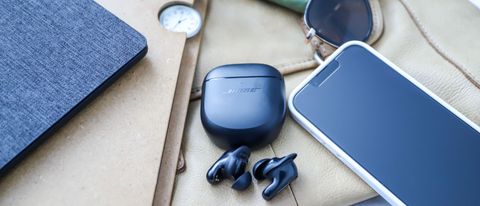 Bose QuietComfort Earbuds 2 lying beside their case and a phone