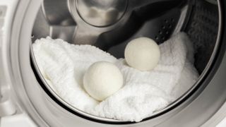 Two wool dryer balls in a clothes dryer on a white towel