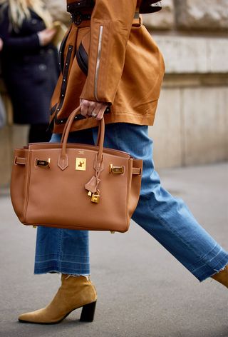 a street-style photo of a woman carrying a Hermés bag in a story about how to buy an hermés bag