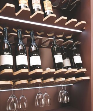 Wine in wooden shelf holders, wine glasses hung beneath each bottle
