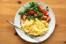 Scrambled egg served with a side salad of tomatoes and greens