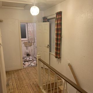 hallway before makeover with white wall white door and wooden flooring