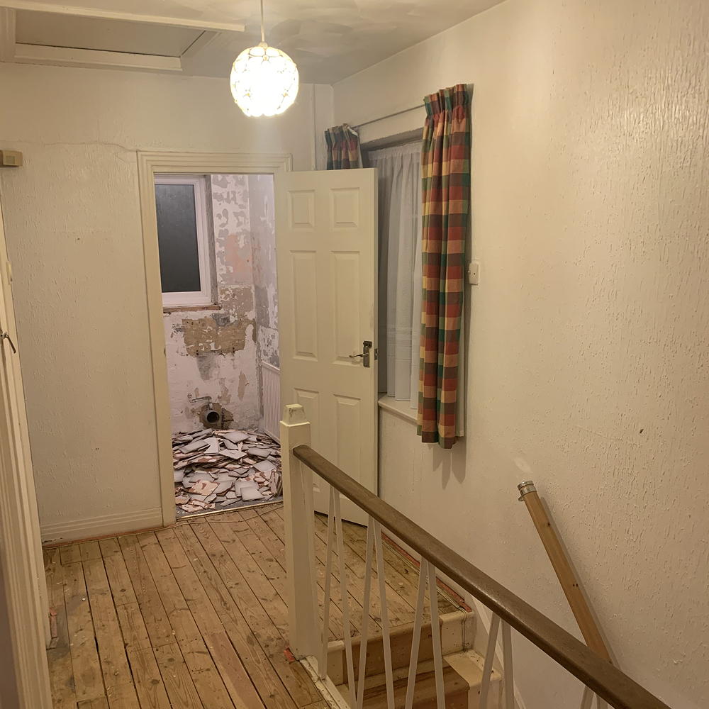 hallway before makeover with white wall white door and wooden flooring