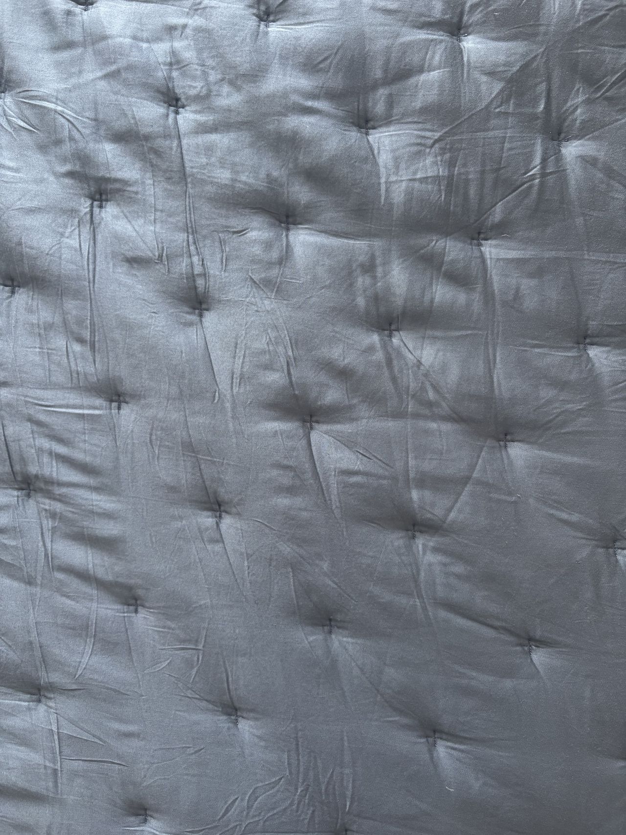 a close-up look of a blue quilt with tufting details (UGC image).