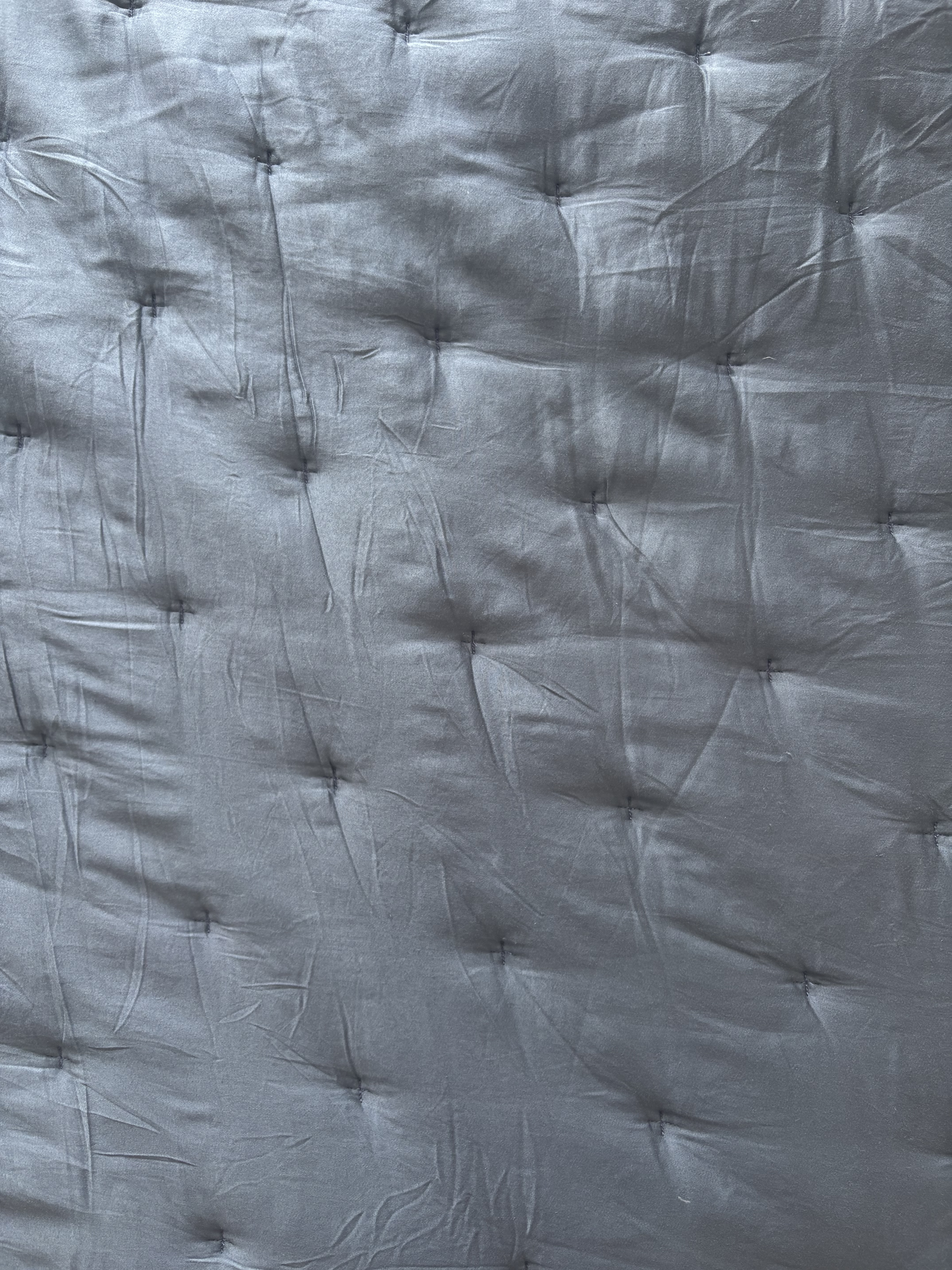 a close-up look of a blue quilt with tufting details (UGC image).