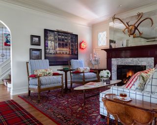 Living room with fireplace, striped armchairs, patterned rug and plaid rug
