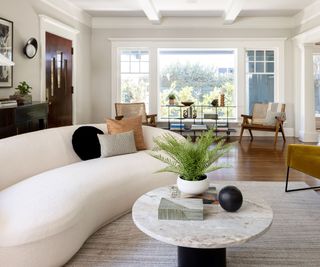 living room with white sofa and mustard accent chairs and round marble coffee table