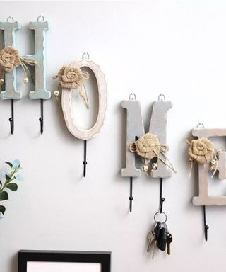 A white wall with decorations that spell out 'home' with flowers on