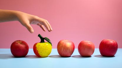 A woman picks an odd-looking apple instead of an average one.