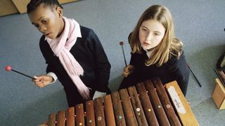 Two young children playing xylophone