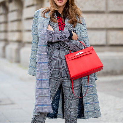 Woman sporting a red Birkin bag for streetwear photo during Berlin Fashion Week.