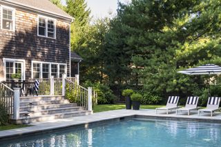 backyard in the Hamptons with swimming pool and striped parasols by BHDM Design