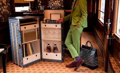 Man in green suit stood next to open luggage trunk