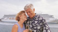 A mature couple on a cruise stand in front of their boat.