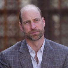 Prince William wears a gray plaid suit and a white suit and looks pensive