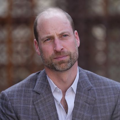 Prince William wears a gray plaid suit and a white suit and looks pensive