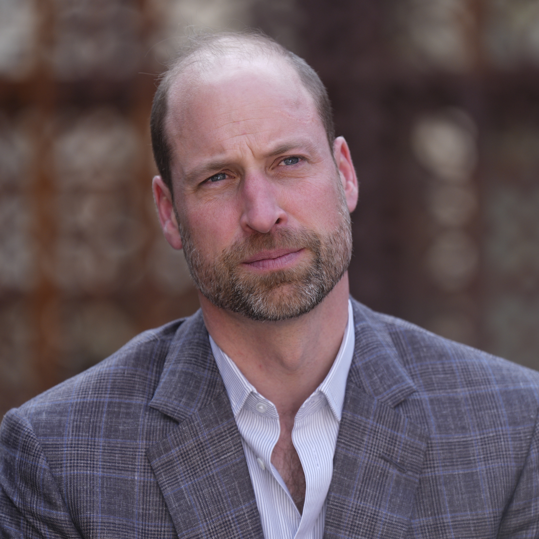 Prince William wears a gray plaid suit and a white suit and looks pensive