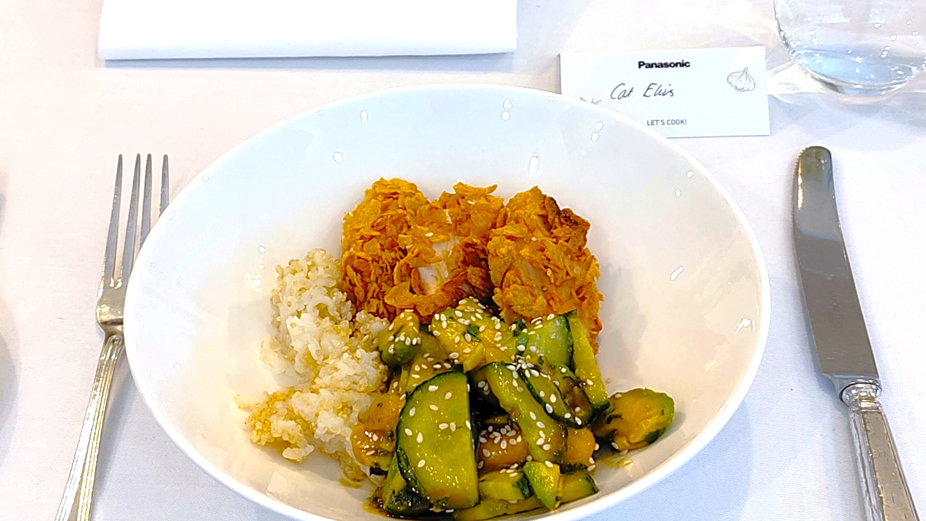 Crispy chicken, avocado salad, and rice on plate with knife and fork