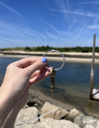 Emma Childs holding her childhood Cape Cod bracelet as a key ring.