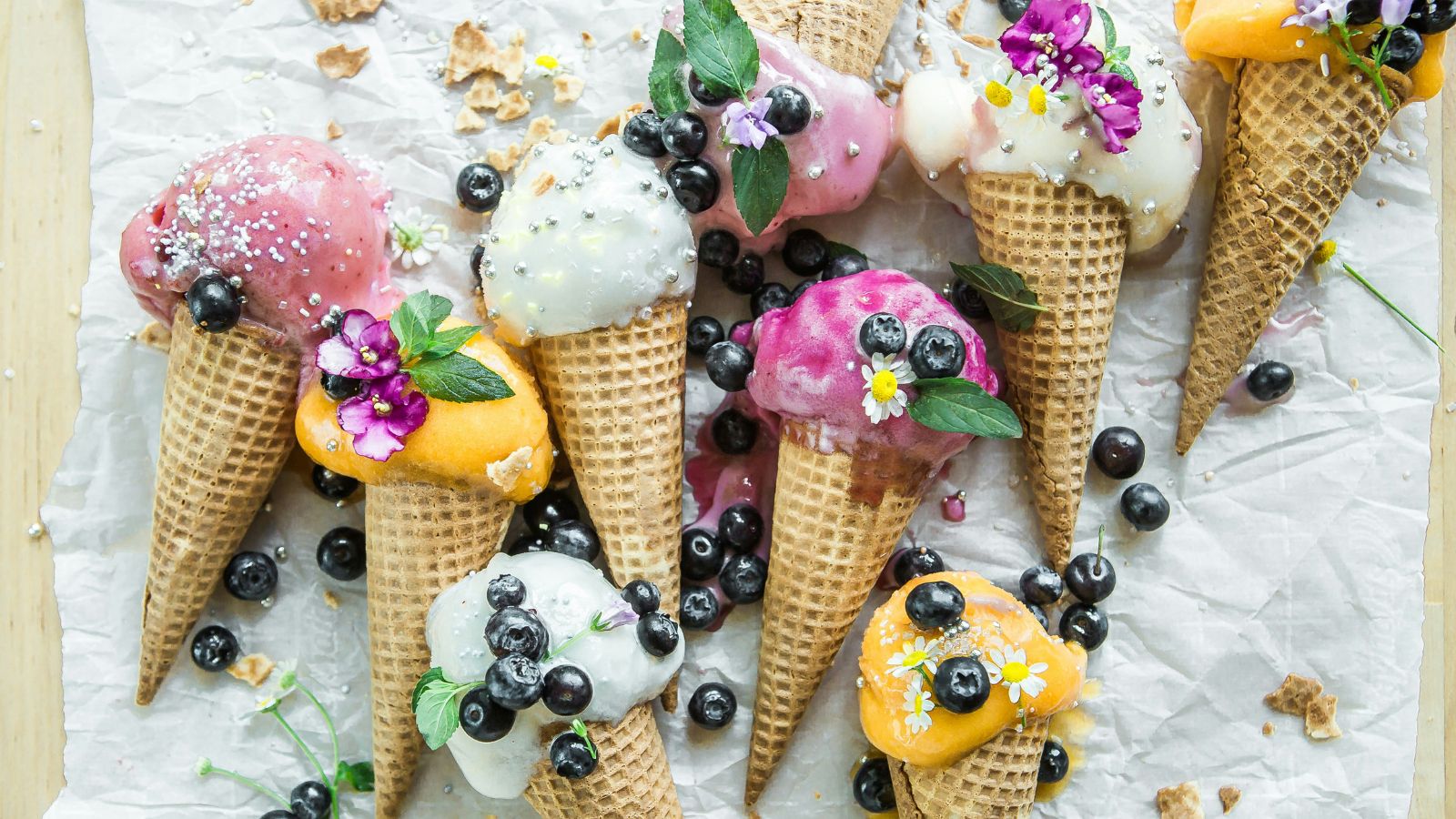 Aerial view of waffle cones filled with fruit sorbet and topped with blueberries and edible flowers