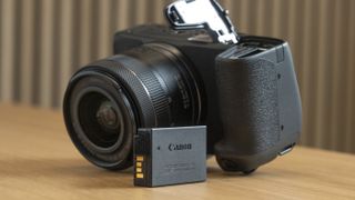 Canon EOS R8 on a table side upside down with battery door open and battery on the table