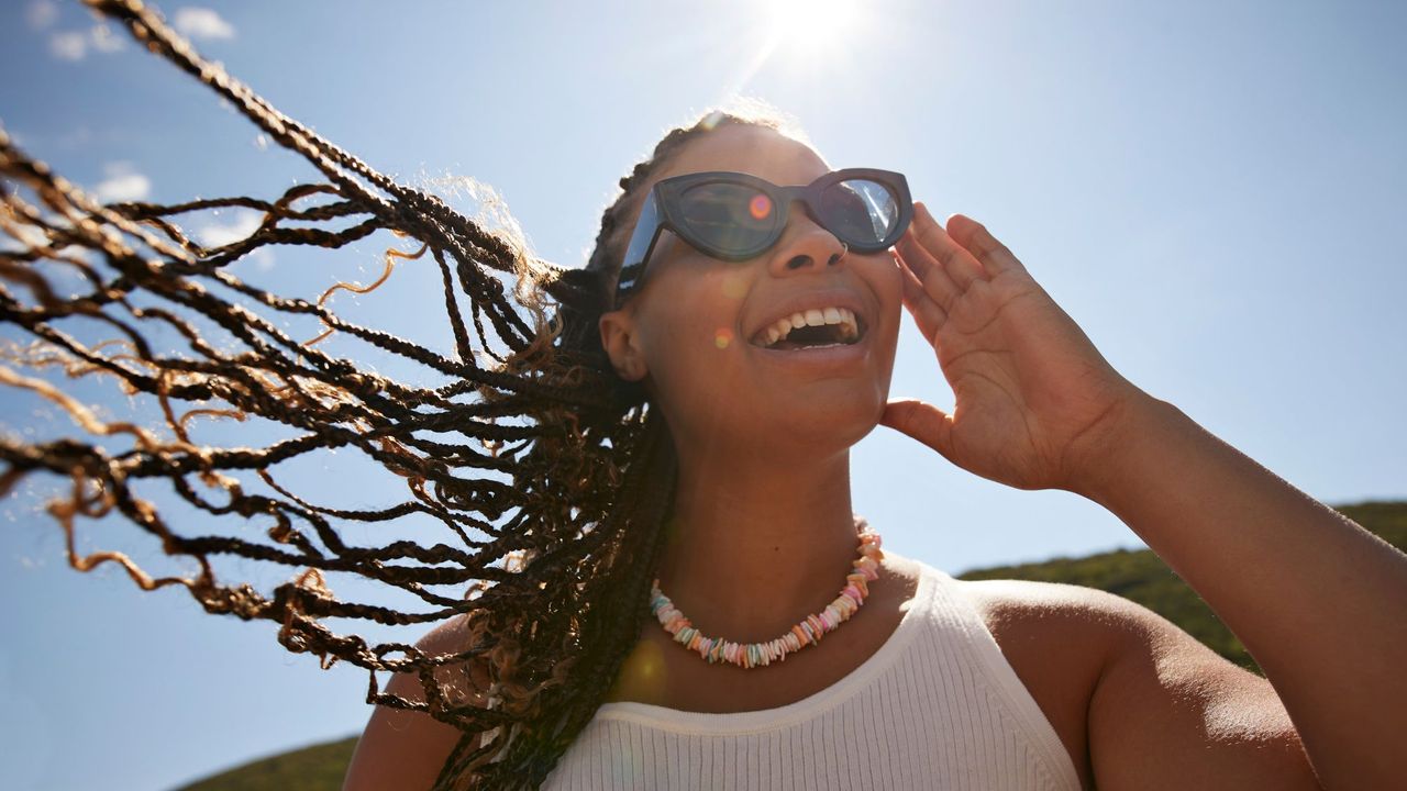 Woman with braids wearing sunglasses in the sunshine