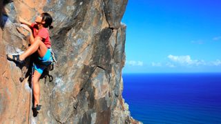 A woman climbing a vertical rockface