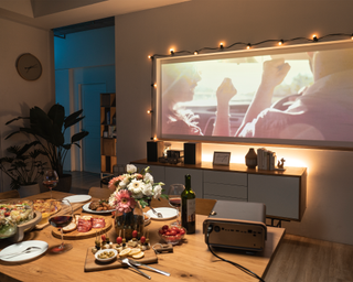 A charcuterie setup with fairy lights and a projector displaying a movie in a living room