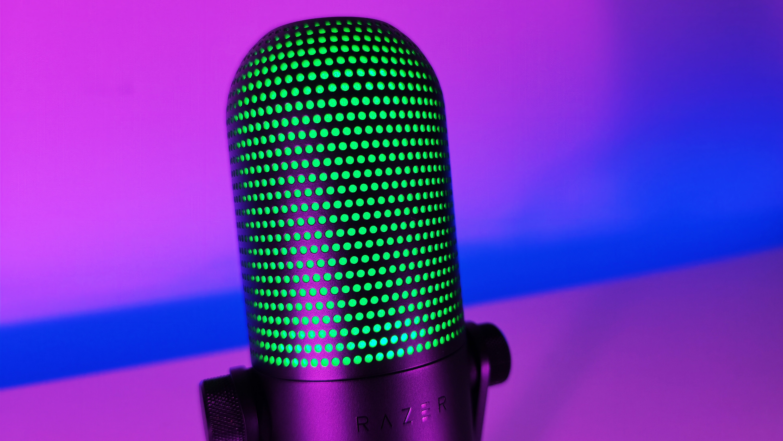 Close-up of the upper mesh grille of the Razer Seiren V3 Chroma microphone glowing green with RGB lighting.