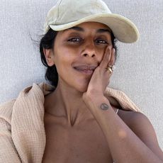 Monikh wearing cap and natural skin possibly with tinted SPF