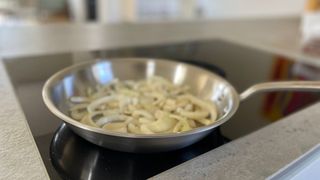 The frying pan from the Made In 10-piece Stainless Steel Pan Set cooking onion