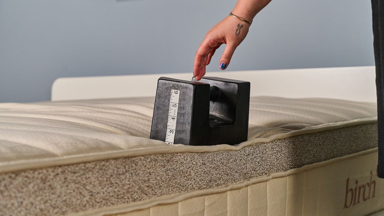 A Tom's Guide tester placing a weight on the edge of the Birch Luxe Natural mattress to measure its edge support