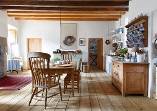 Dining room with kitchen beyond with table and chairs and sideboard and wood floor