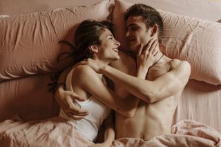 Happy young couple lying in bed