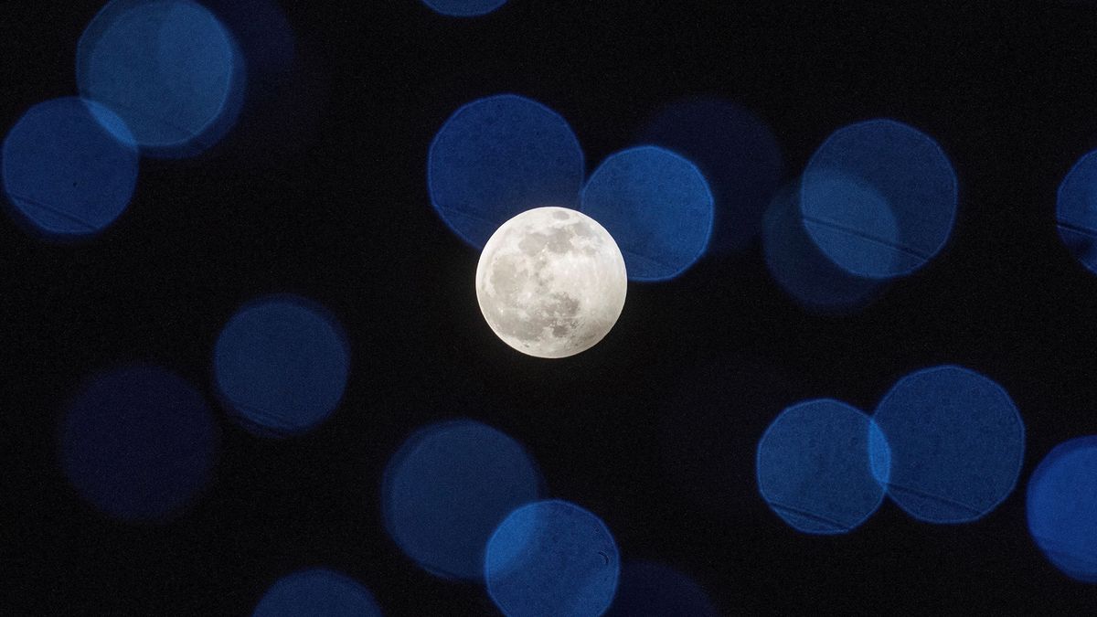 A picture taken on Jan. 10, 2020 shows the Full Wolf Moon rising behind Christmas street decorations during the penumbral lunar eclipse in Skopje, Macedonia.