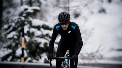A cyclist riding against snowy trees