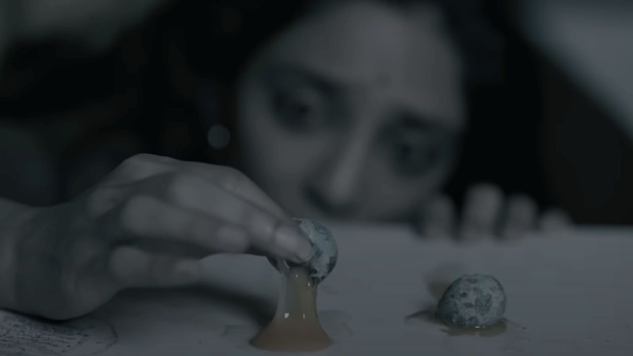 Sobhita Dhulipala pulling an oozing egg from surface in Ghost Stories
