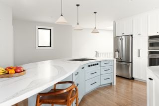 A kitchen with white cabinets, and blue lower cabinets