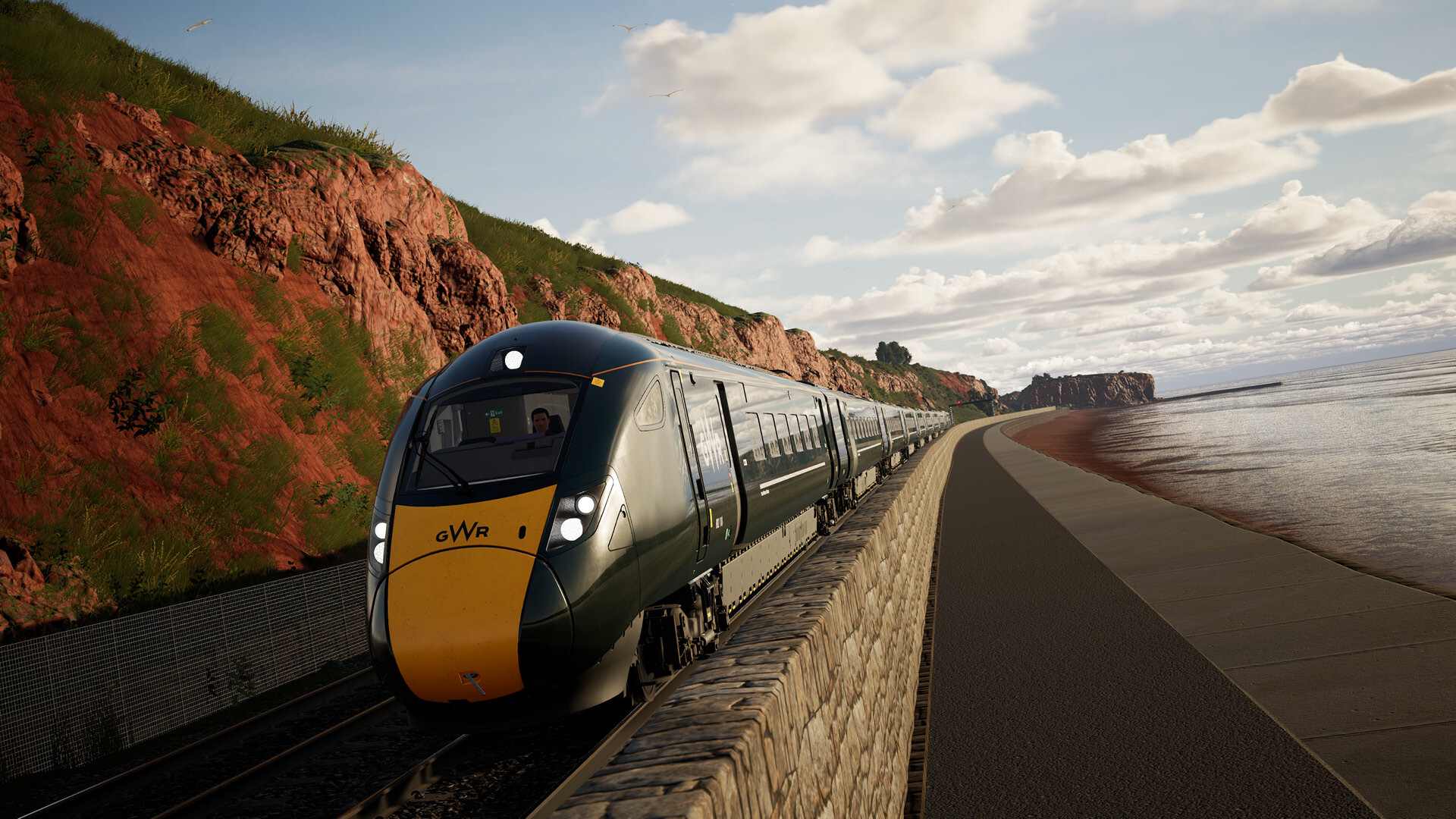 A promotional screenshot from Train Sim World 6 showing a GWR train driving along the Devon coast. 