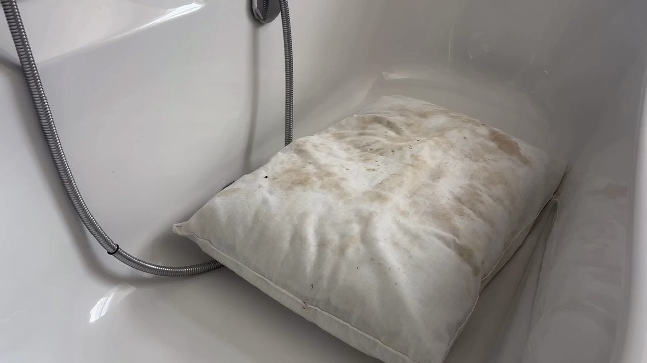 A stained pillow in a bathtub.