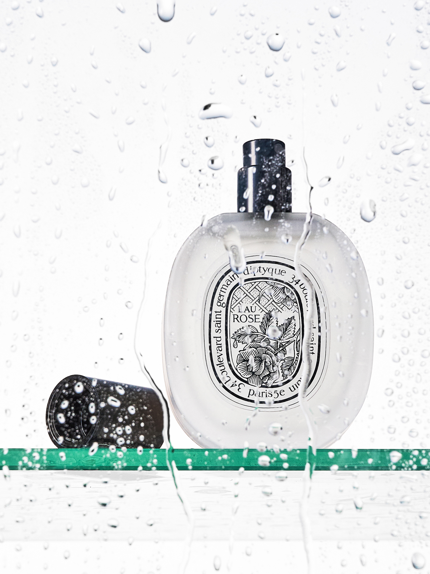 A Diptyque floral hair perfume behind a shower screen