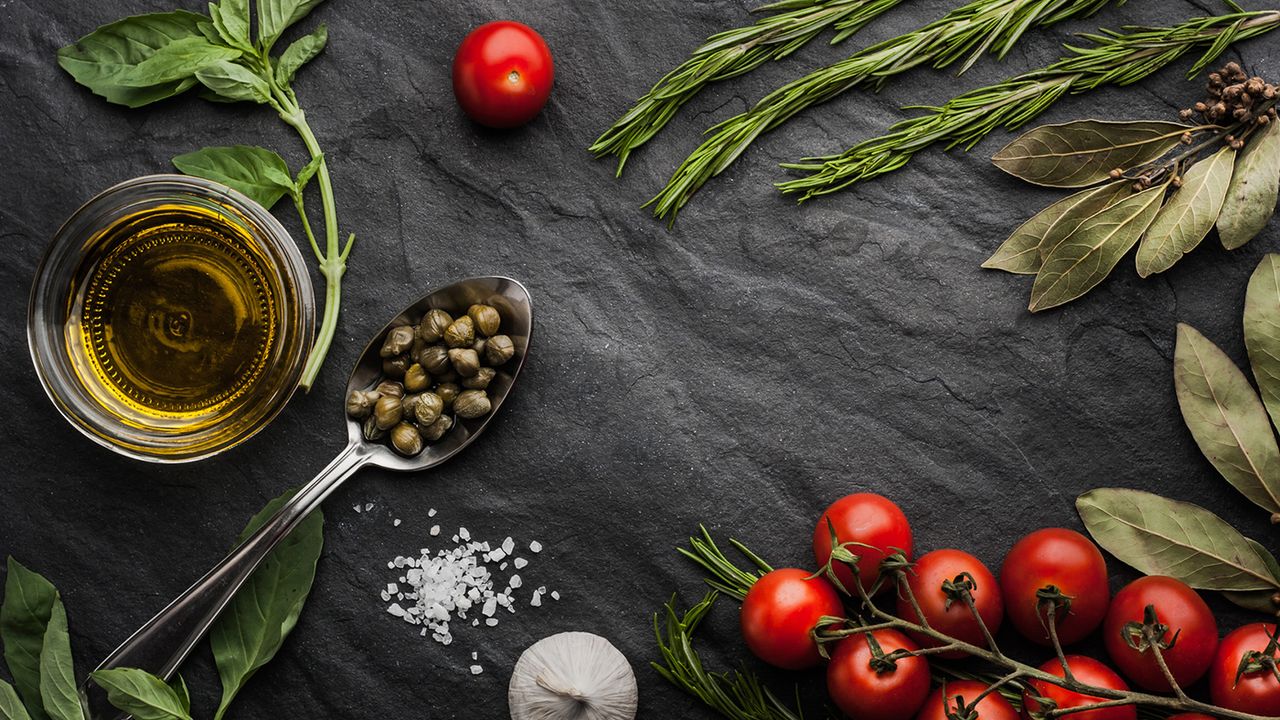 Herbs mix with tomatoes and olive oil on the black stone table